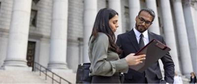 A man and a woman standing outside and looking at a tablet.