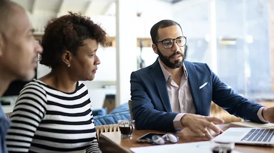 Three professionals collaborating in front of a computer, as one of them demonstrates cybersecurity to his two colleagues.