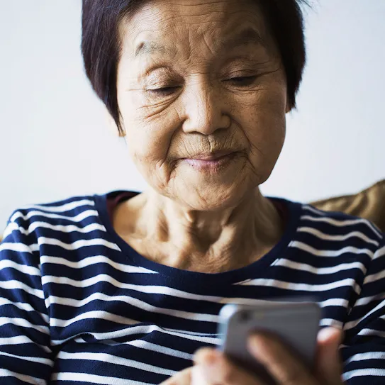 Photograph of an older  woman browsing the web on her phone — an overlay shows us she has searched for “airline customer support.”